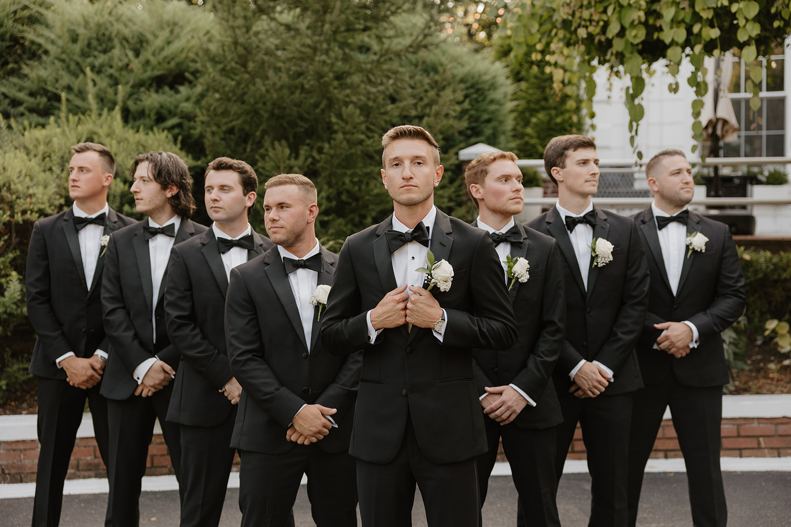Groom poses confidently with his groomsmen, who look away in a sharp, coordinated group portrait.